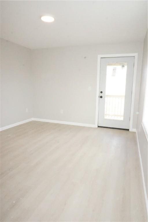 empty room featuring recessed lighting, baseboards, and light wood finished floors