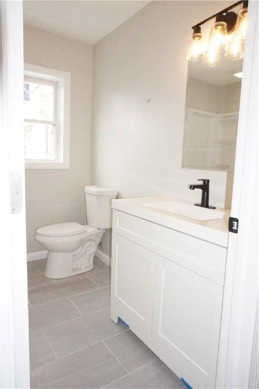 bathroom featuring baseboards, toilet, vanity, and tile patterned flooring