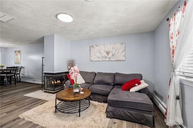 living room featuring baseboards, baseboard heating, wood finished floors, and a textured ceiling