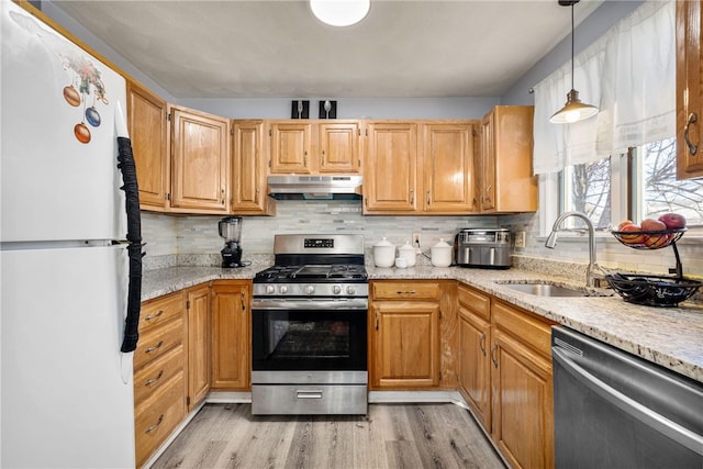 kitchen featuring light wood finished floors, a sink, decorative backsplash, under cabinet range hood, and appliances with stainless steel finishes