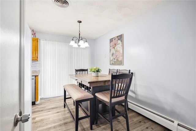 dining room featuring a chandelier, visible vents, light wood-type flooring, and a baseboard heating unit