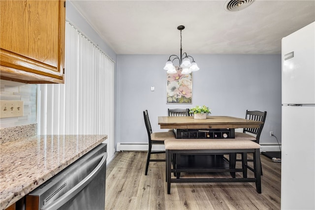 dining area with visible vents, a chandelier, light wood-style flooring, and a baseboard radiator