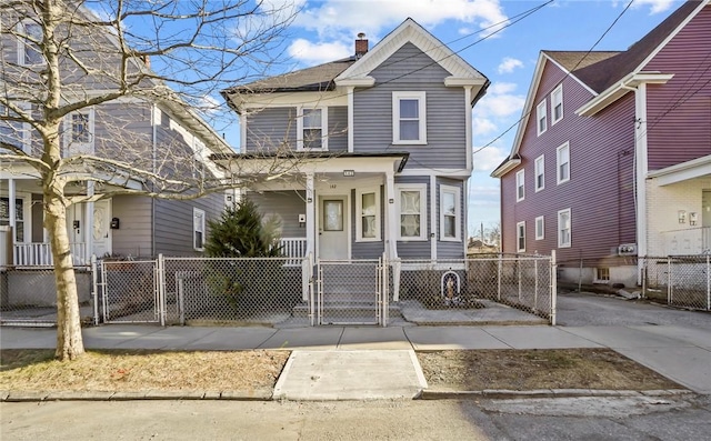 view of front of property with a fenced front yard, a porch, a chimney, and a gate