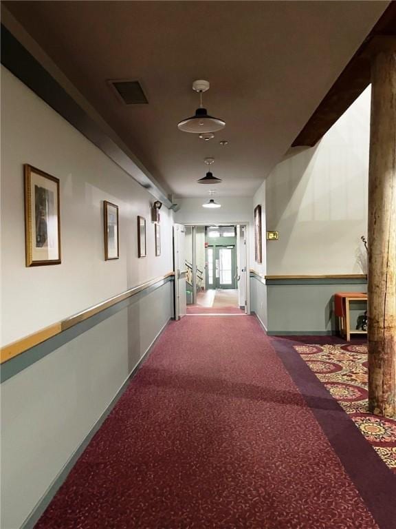 hall featuring carpet flooring and visible vents