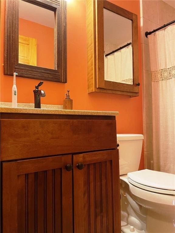 bathroom with curtained shower, toilet, and vanity