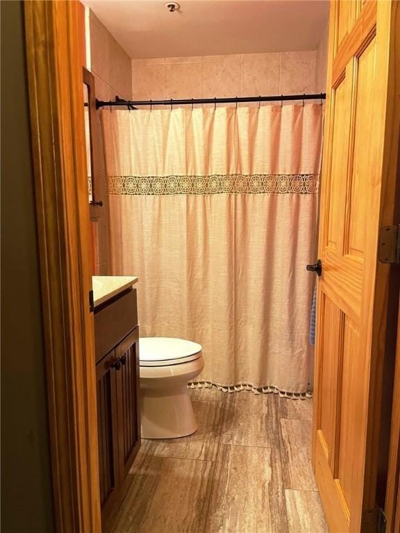 bathroom with vanity, curtained shower, toilet, and wood finished floors