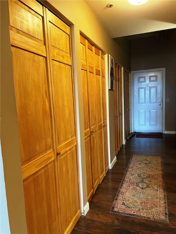 hall featuring baseboards and dark wood-type flooring