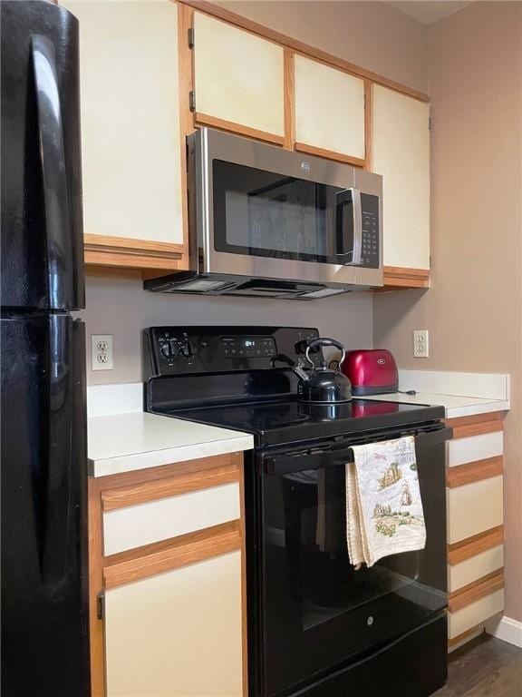 kitchen with black appliances, wood finished floors, and light countertops