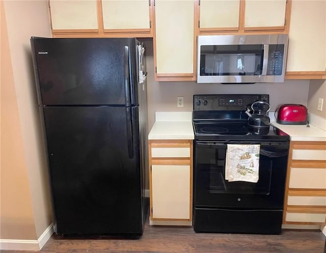 kitchen with dark wood-style floors, black appliances, light countertops, and baseboards