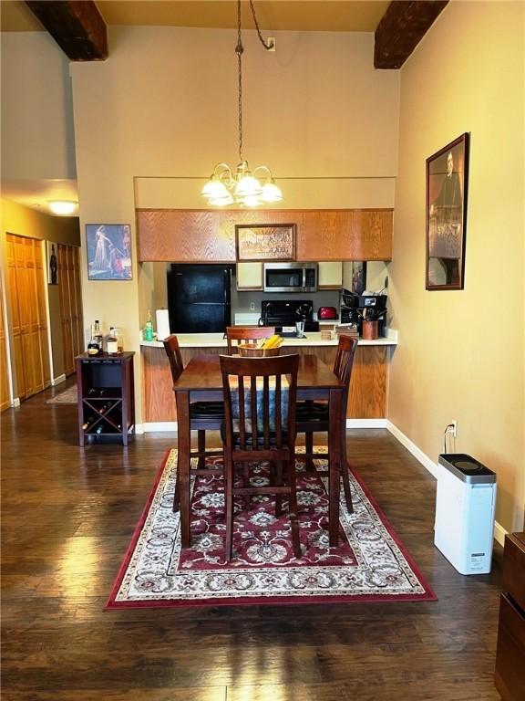 dining room featuring beamed ceiling, baseboards, an inviting chandelier, and wood finished floors