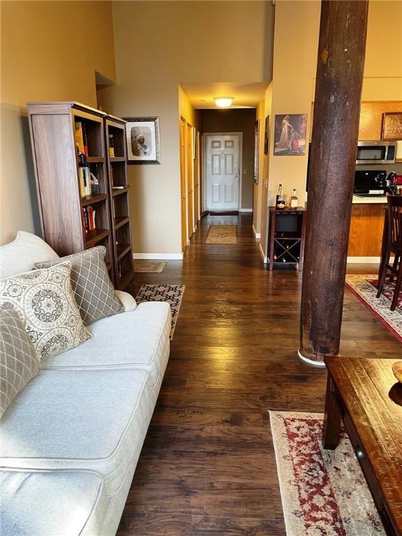 living area with a high ceiling, baseboards, and wood finished floors