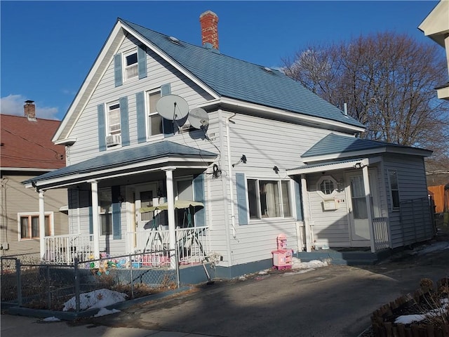 view of front facade featuring fence, covered porch, and a chimney