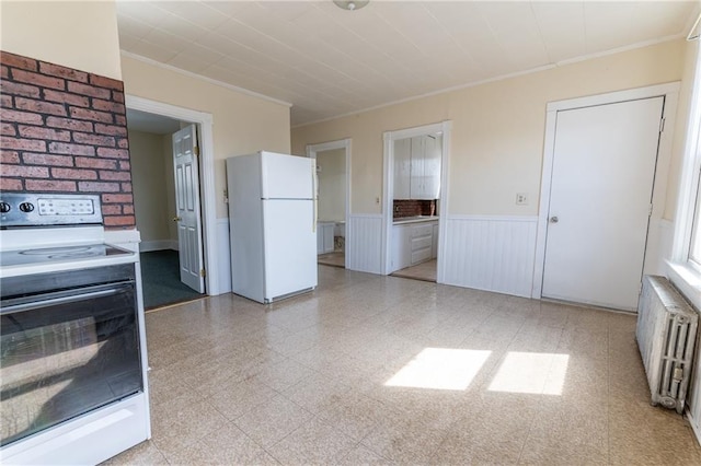 kitchen with radiator heating unit, ornamental molding, wainscoting, freestanding refrigerator, and electric range