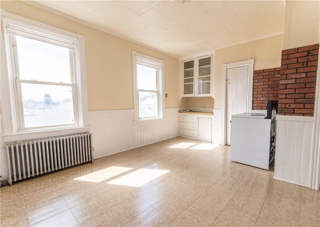 spare room with wainscoting, radiator, and light floors