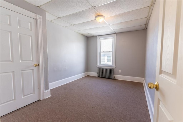 carpeted spare room with a drop ceiling, baseboards, and radiator