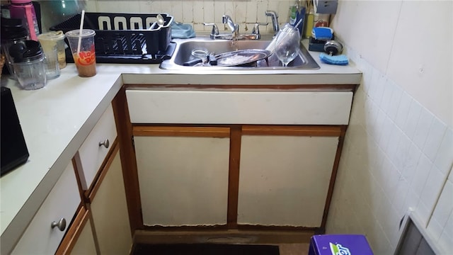 kitchen featuring tile walls, light countertops, and a sink