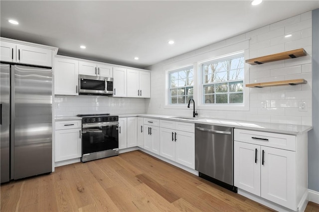 kitchen with a sink, appliances with stainless steel finishes, light countertops, and light wood finished floors