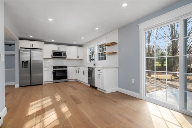 kitchen with white cabinetry, light wood finished floors, backsplash, and appliances with stainless steel finishes