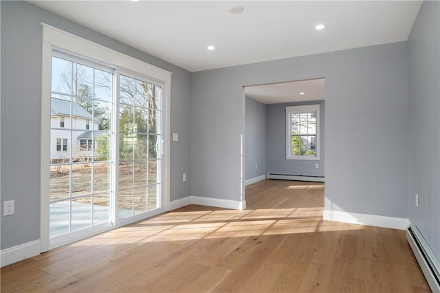 spare room featuring light wood finished floors, baseboards, and a baseboard radiator