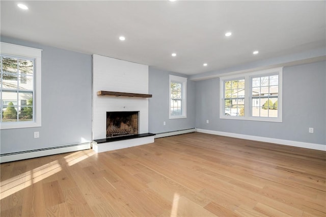 unfurnished living room with a baseboard heating unit, recessed lighting, light wood finished floors, and a large fireplace