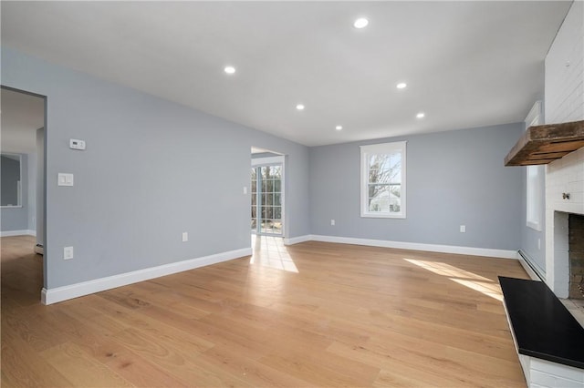 unfurnished living room with a brick fireplace, recessed lighting, baseboards, and light wood finished floors