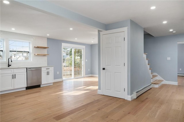 kitchen featuring baseboard heating, stainless steel dishwasher, white cabinets, and light wood finished floors