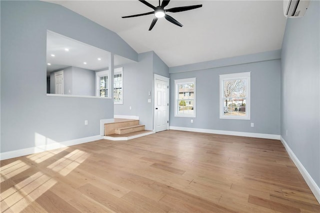 unfurnished living room featuring an AC wall unit, wood finished floors, baseboards, ceiling fan, and vaulted ceiling