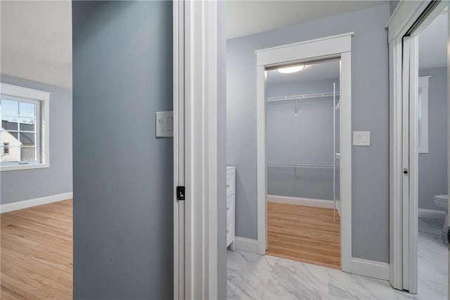 corridor with baseboards and marble finish floor