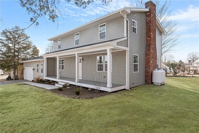 view of front of home featuring driveway, a front lawn, covered porch, an attached garage, and a chimney