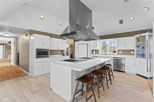 kitchen featuring white cabinetry, stainless steel appliances, a kitchen bar, and island range hood