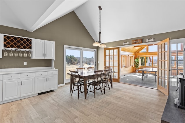 dining room featuring light wood-style floors, a dry bar, and high vaulted ceiling