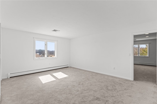 carpeted spare room with a baseboard radiator, plenty of natural light, baseboard heating, and visible vents