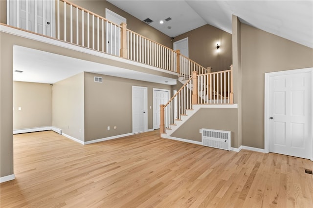 interior space featuring stairway, wood finished floors, baseboards, and high vaulted ceiling