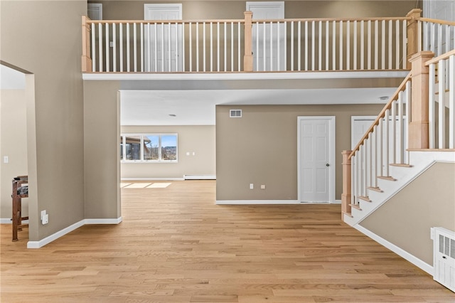 interior space featuring wood finished floors, visible vents, and a towering ceiling