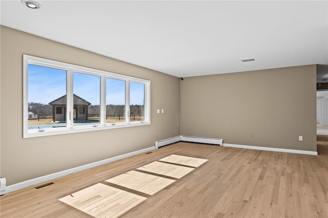 unfurnished room featuring visible vents, baseboards, and a baseboard radiator