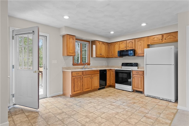 kitchen featuring baseboards, light countertops, recessed lighting, black appliances, and a sink