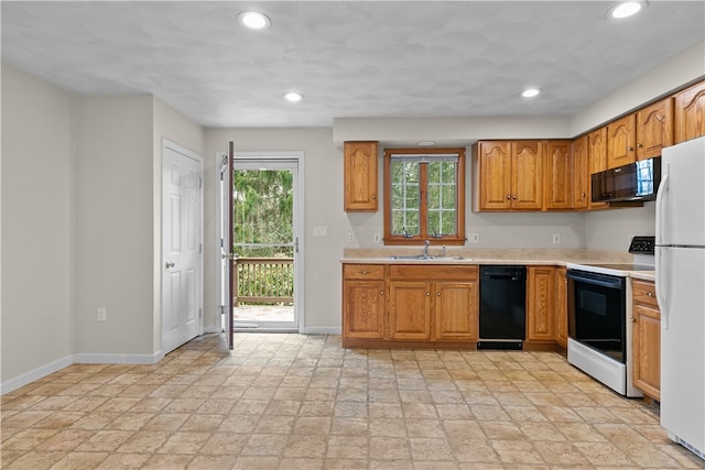 kitchen with a sink, black appliances, recessed lighting, and light countertops