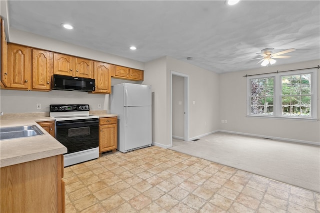 kitchen featuring freestanding refrigerator, a sink, electric range oven, light countertops, and black microwave