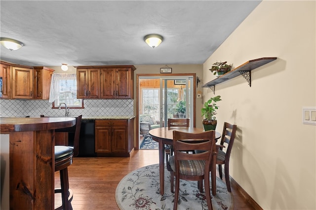 kitchen with wood finished floors, black dishwasher, a healthy amount of sunlight, and backsplash