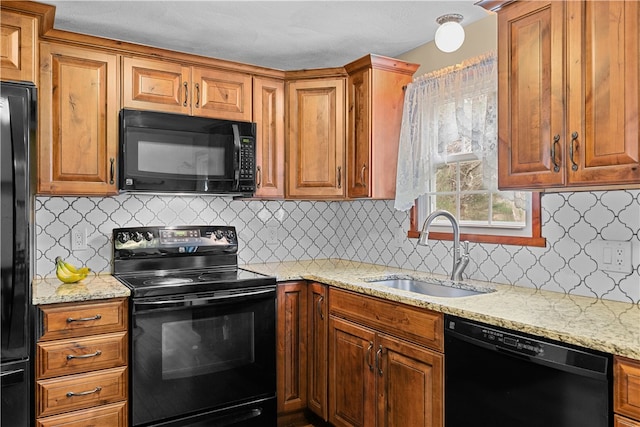 kitchen featuring a sink, light stone counters, black appliances, and brown cabinets