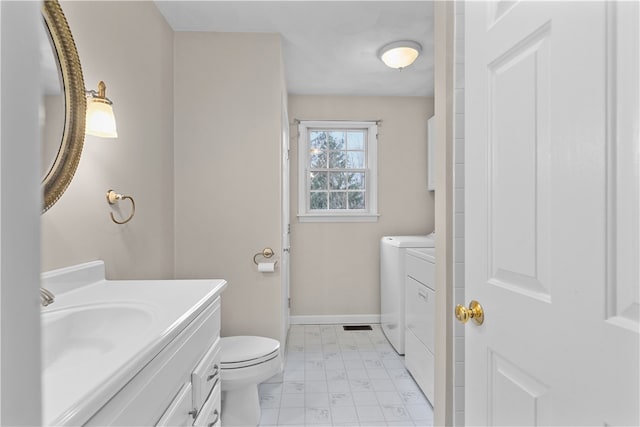 bathroom featuring vanity, baseboards, washer and dryer, toilet, and marble finish floor