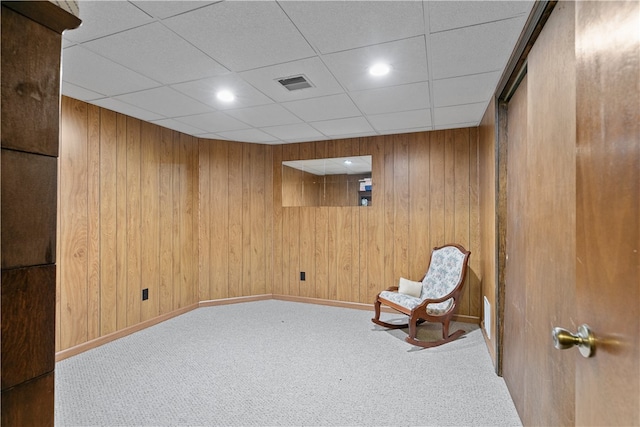 unfurnished room featuring visible vents, carpet floors, and wood walls