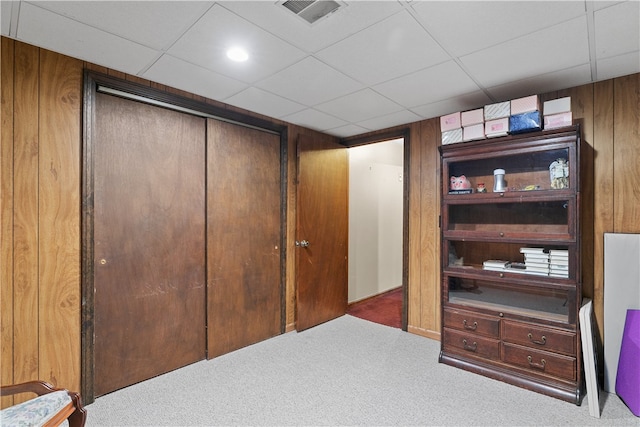 interior space with wooden walls, a drop ceiling, visible vents, and a closet