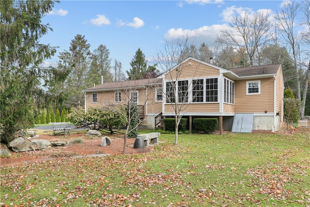 rear view of house with a yard and a sunroom