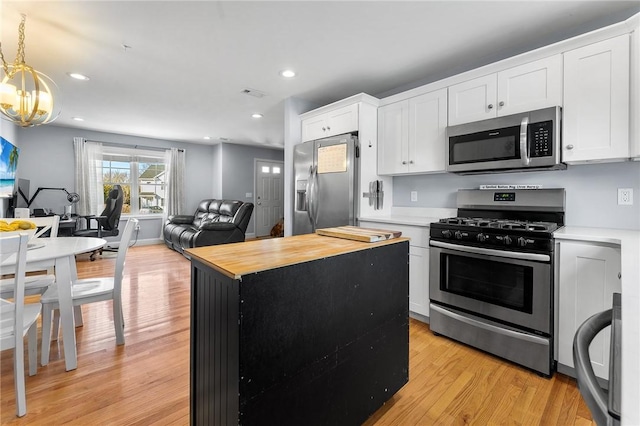 kitchen featuring stainless steel appliances, butcher block countertops, open floor plan, and white cabinetry