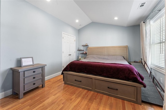 bedroom featuring light wood-type flooring, baseboards, visible vents, and vaulted ceiling