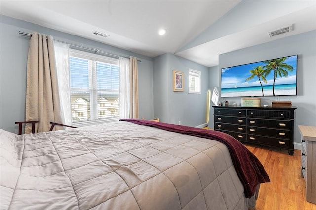 bedroom with light wood-type flooring, visible vents, lofted ceiling, and baseboards