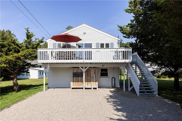 view of front facade featuring stairs, gravel driveway, a deck, and a front lawn