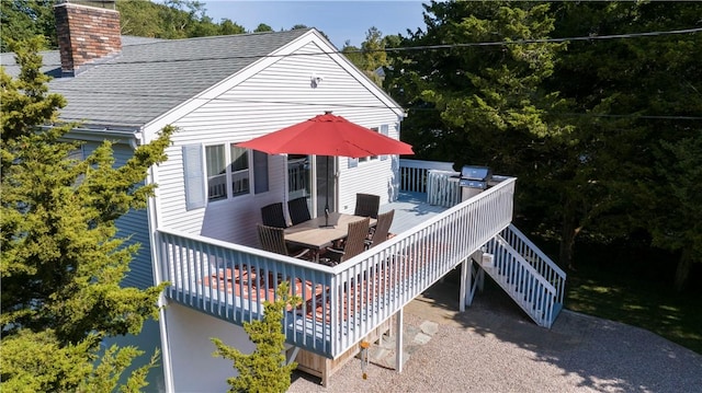 exterior space featuring a chimney, outdoor dining area, a deck, and roof with shingles