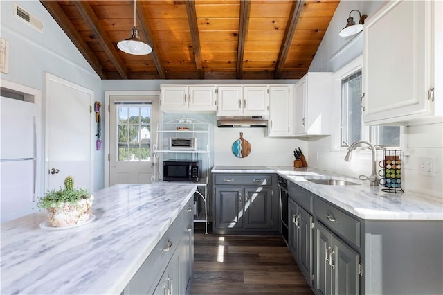 kitchen featuring visible vents, gray cabinetry, vaulted ceiling with beams, under cabinet range hood, and a sink